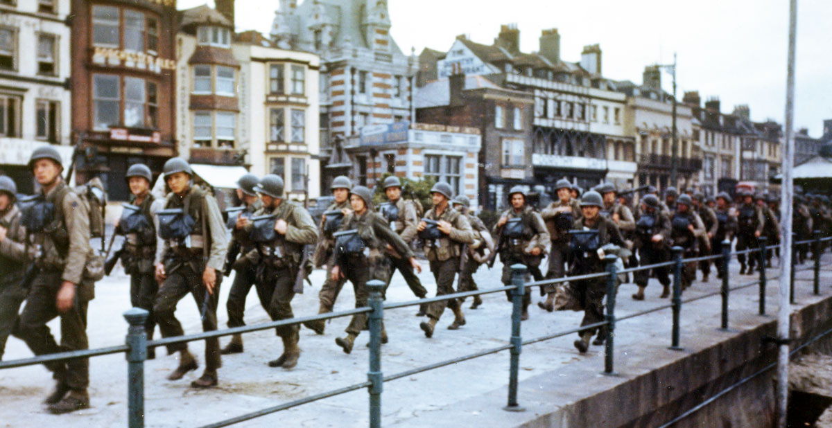 Troops march through an English seaside town toward their ships before D-Day.